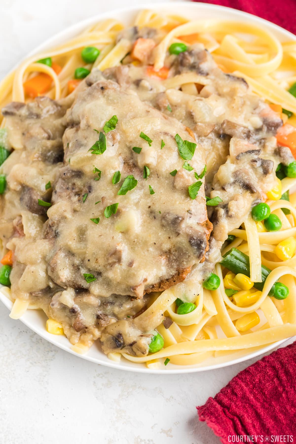 plate of pasta with baked pork chops with cream of mushroom soup and gravy over top of it.