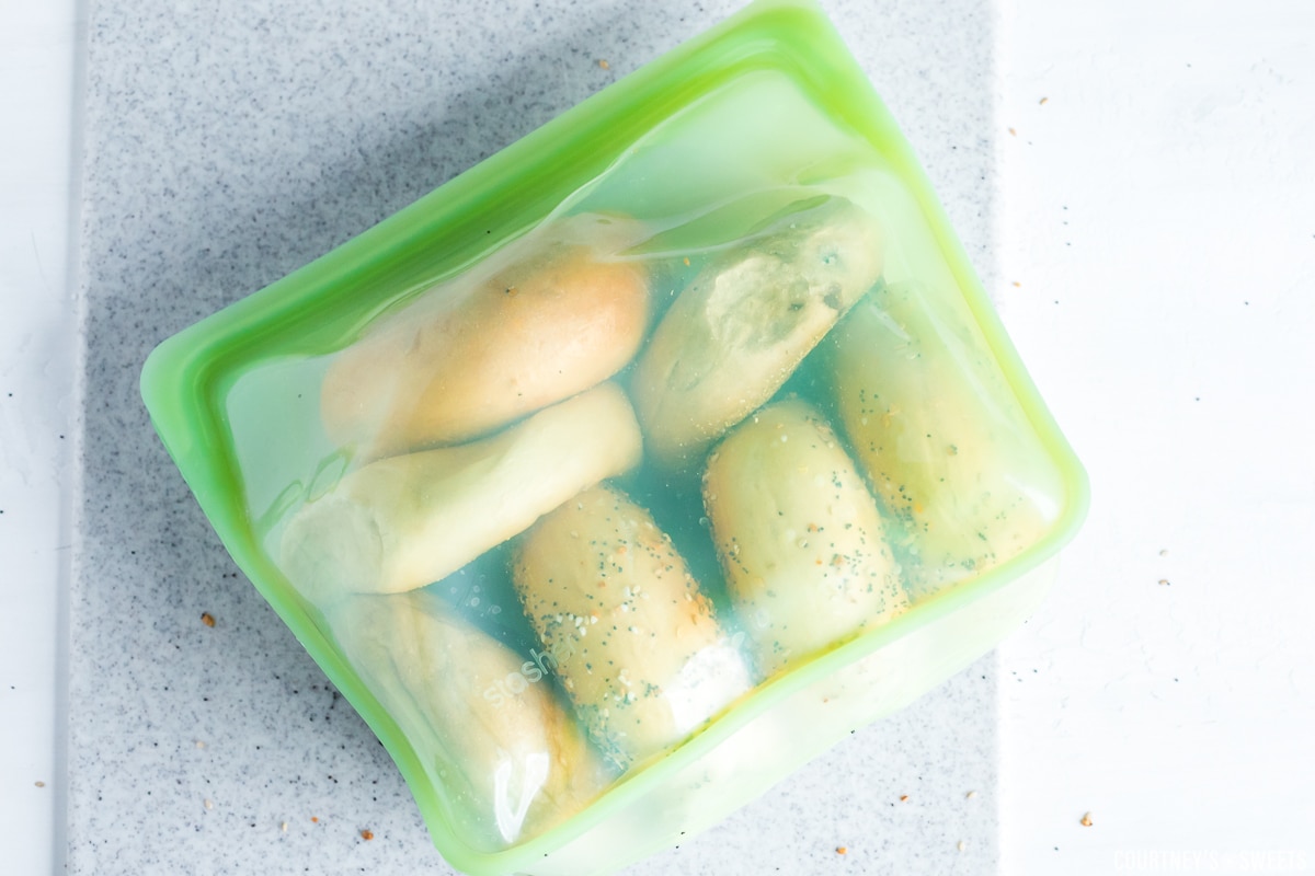 7 bagels in a green stasher bag on a cutting board.