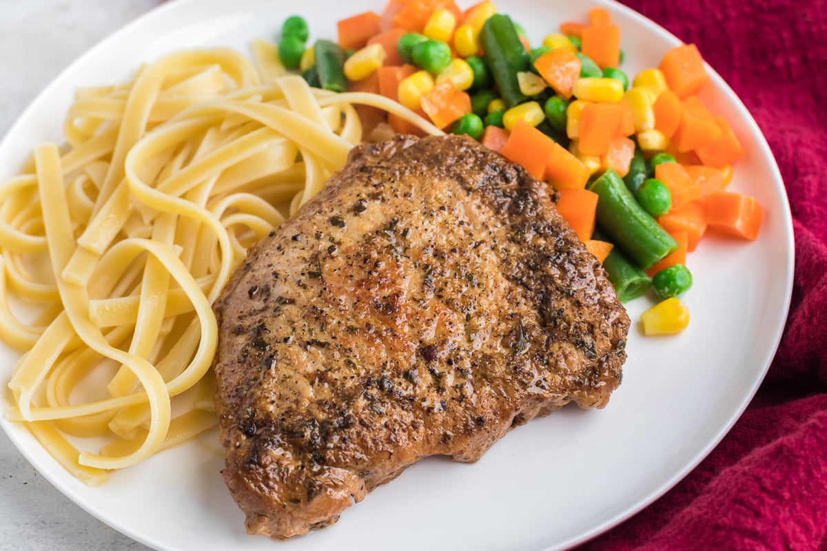 instant pot pork chop on a plate with noodles and veggies.