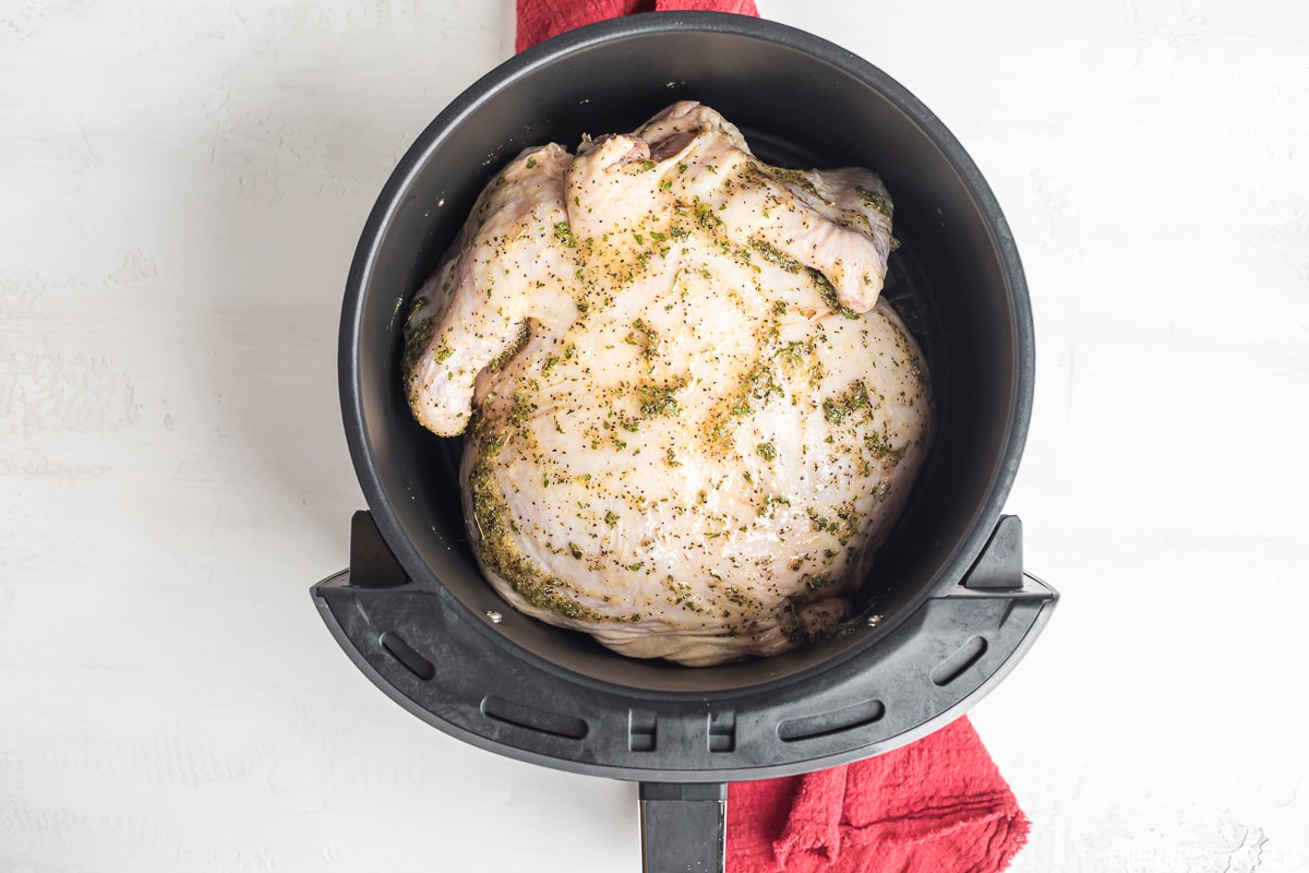 raw whole chicken in air fryer basket.