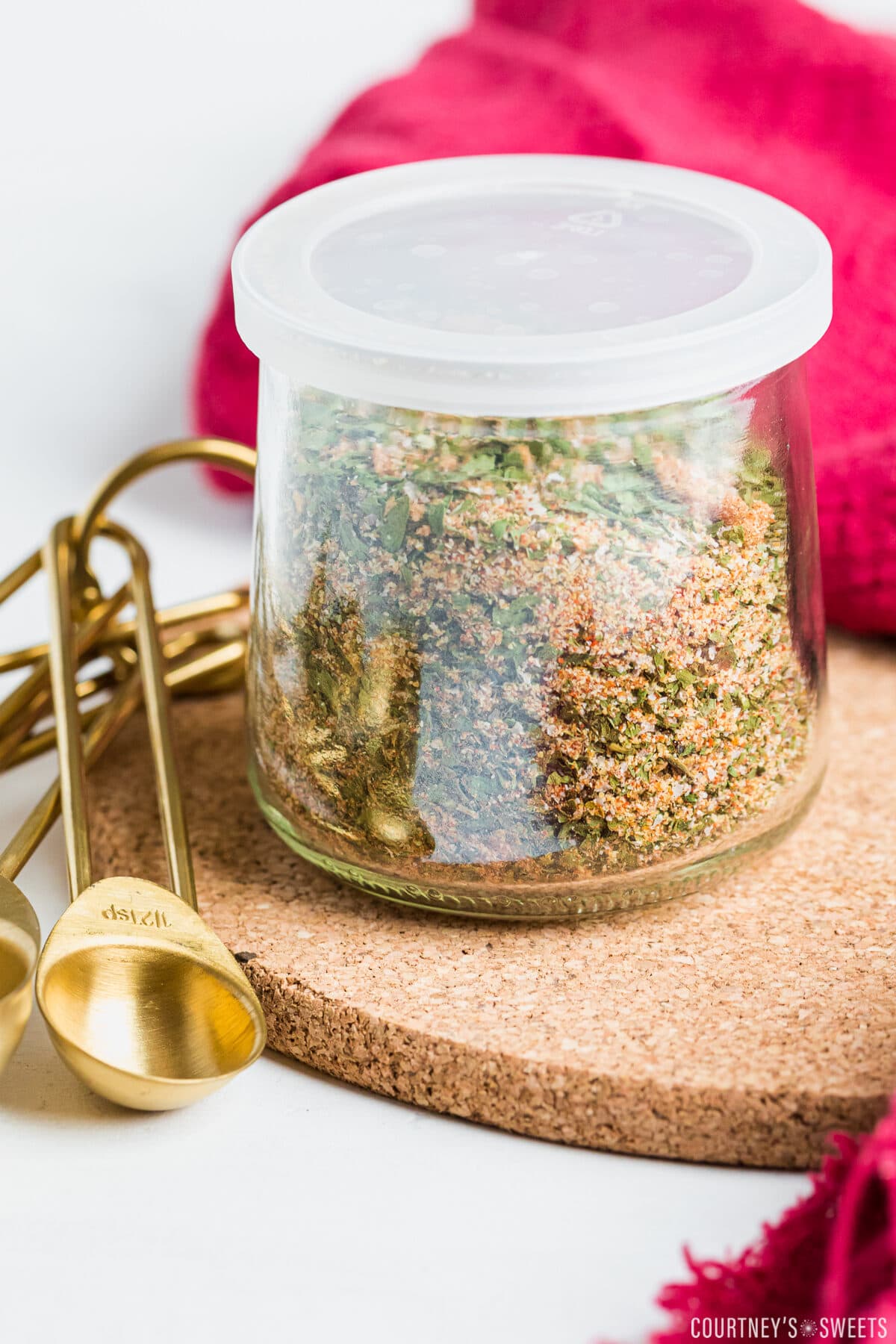 chicken seasoning blend in a glass jar on a cork pot holder.