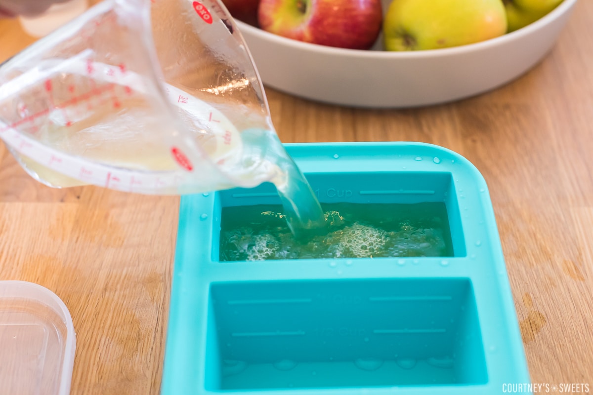 measuring cup pouring broth into souper cubes.