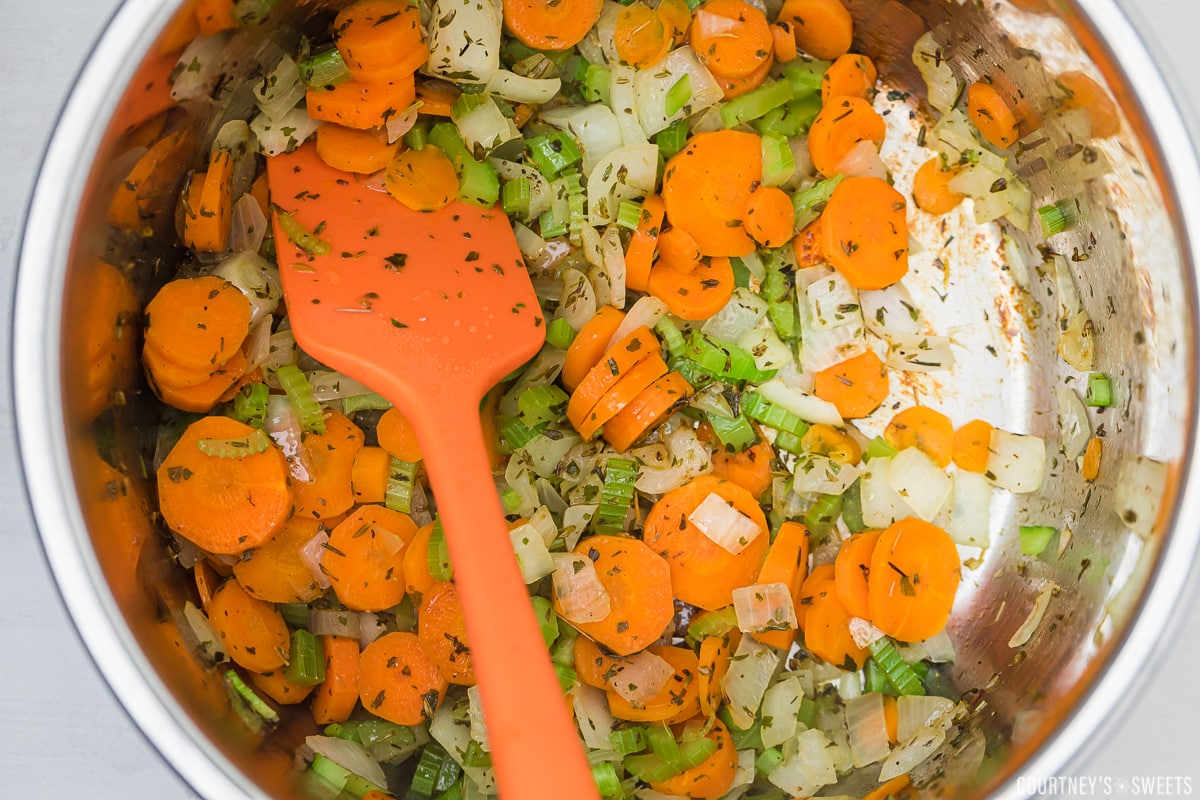 orange spatula stirring soup vegetables in instant pot.