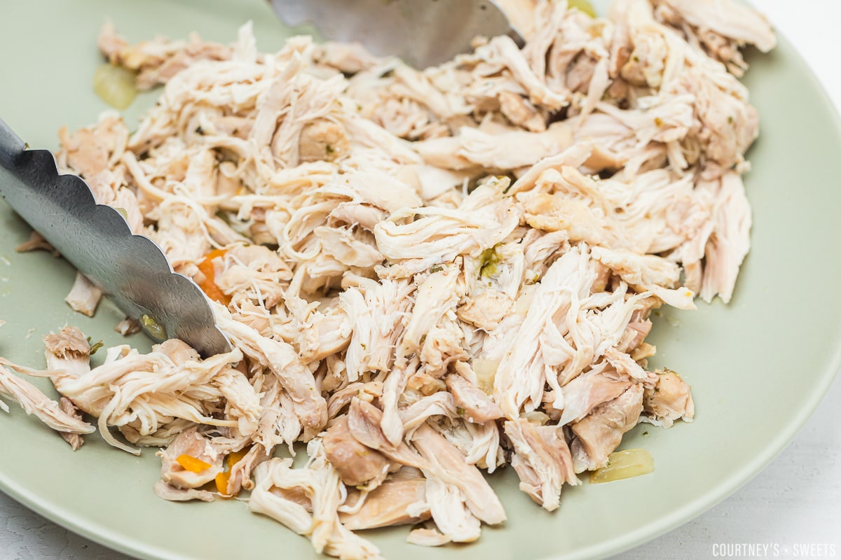 shredded chicken thighs on a green plate.
