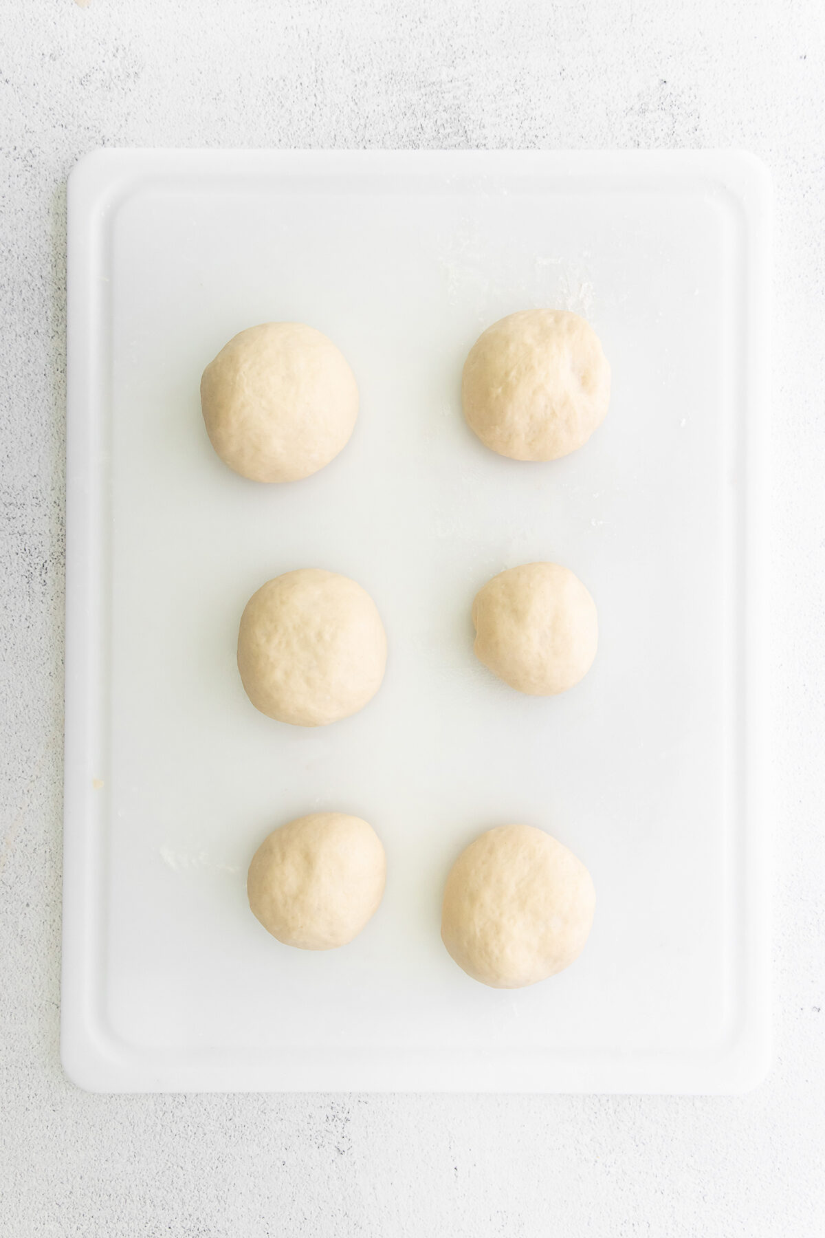 5 dough balls on a cutting board.