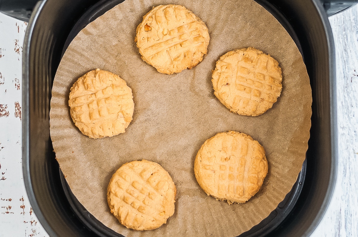 air fried peanut butter cookies on parchment paper in air fryer basket.