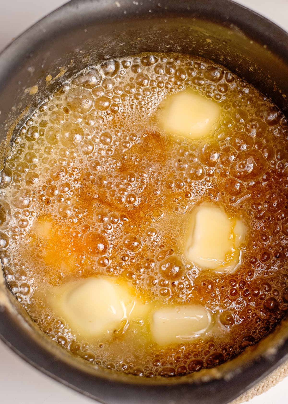 slices of butter melting in a saucepan to make caramel sauce.