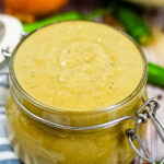 open glass jar filled with green enchilada sauce.
