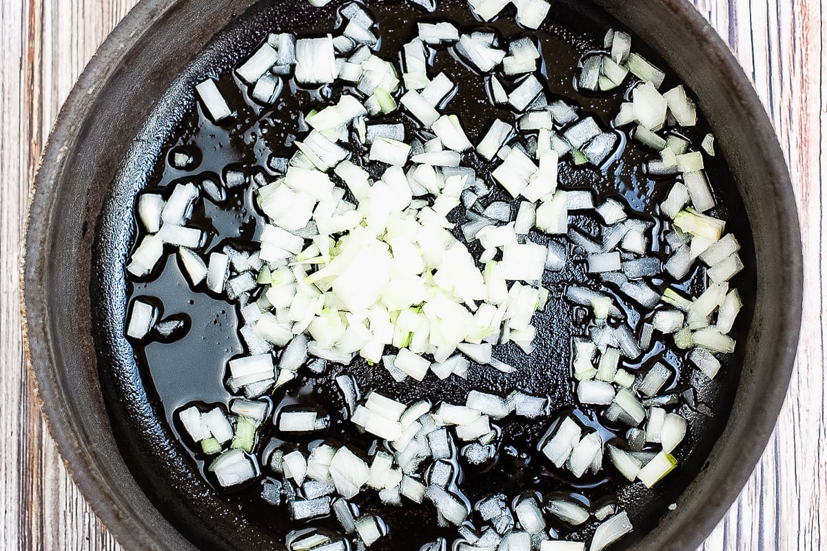 onions cooking in a frying pan with oil.