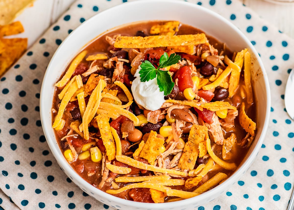 close up of chicken taco soup in a bowl with crispy tortilla strips.