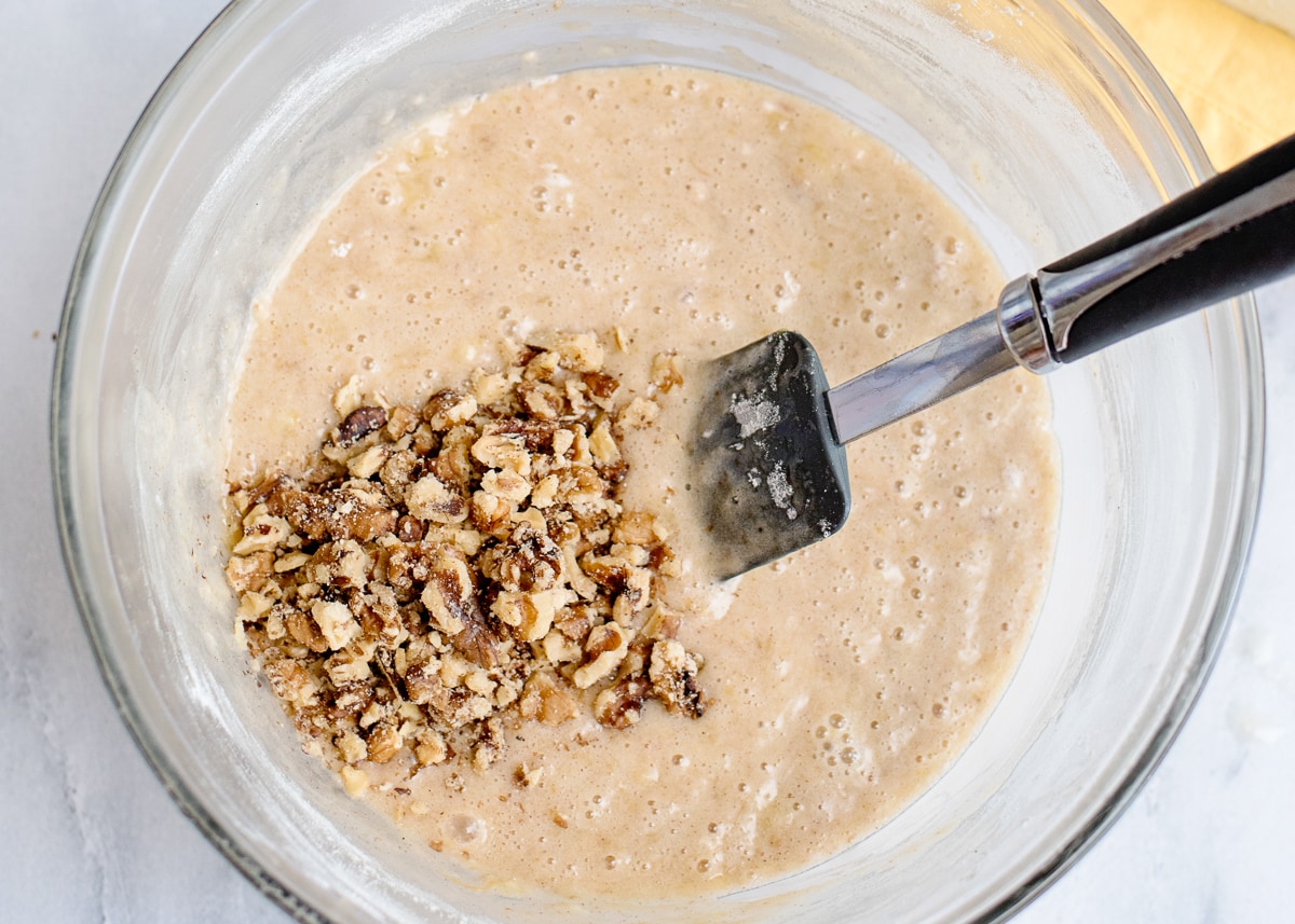 banana nut cake batter with chopped walnuts in a bowl with a rubber cake spatula.