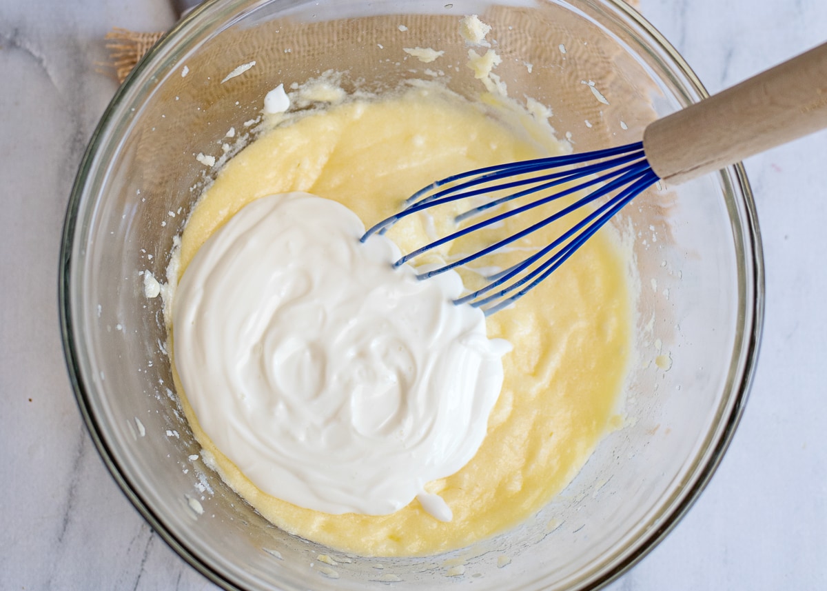 mixing wet ingredients for a cake in a glass bowl with a whisk.