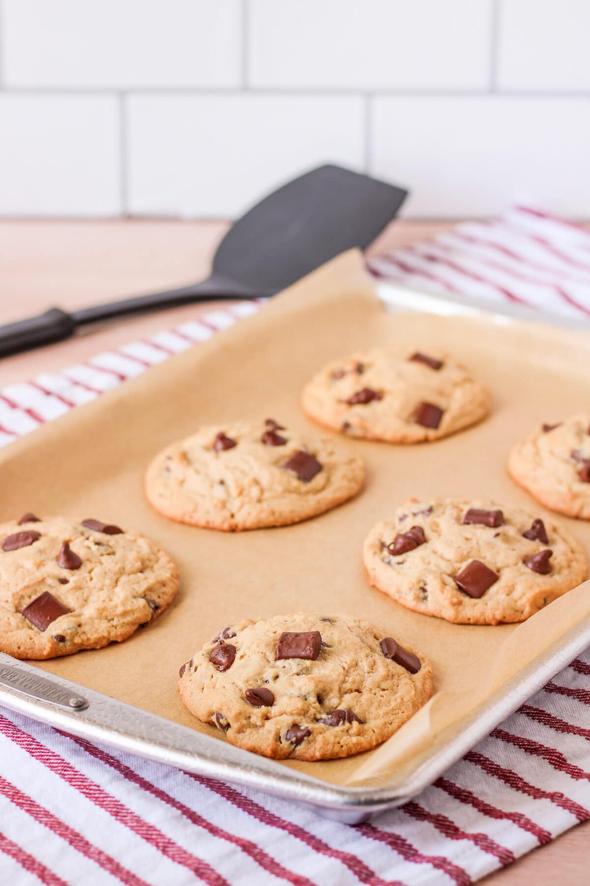 cookies fresh out of the oven on a baking sheet on a white and red striped towel.