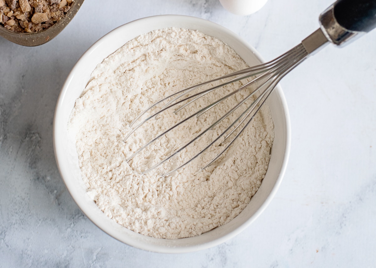 whisked dry ingredients in a white bowl with a whisk still inside.