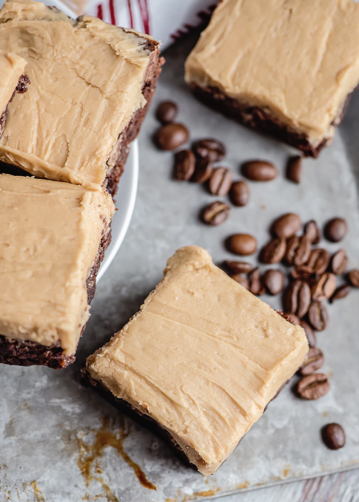 frosted coffee brownies on a sheet pan with coffee beans scattered.