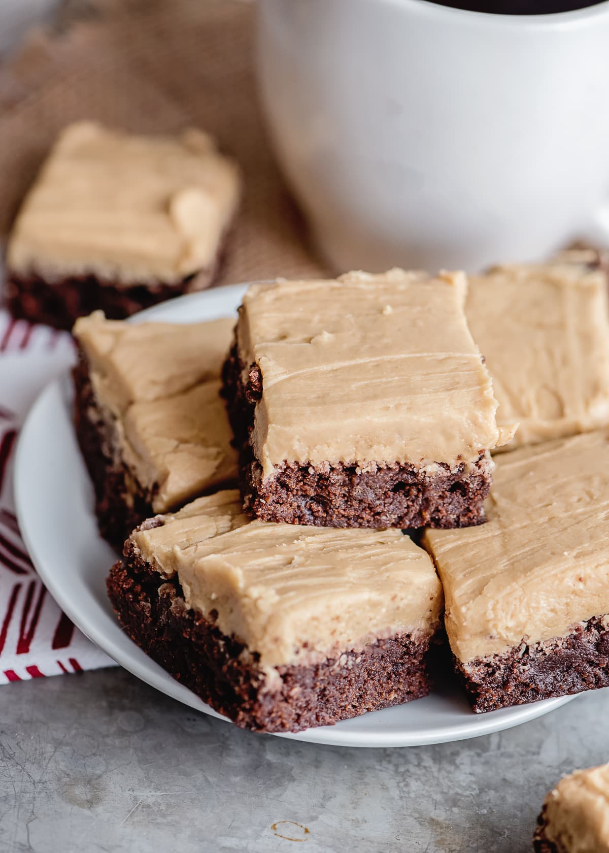 frosted coffee brownies on a white plate stacked.