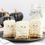 mummy rice krispie treats on a black plate with one on the backdrop below the plate.