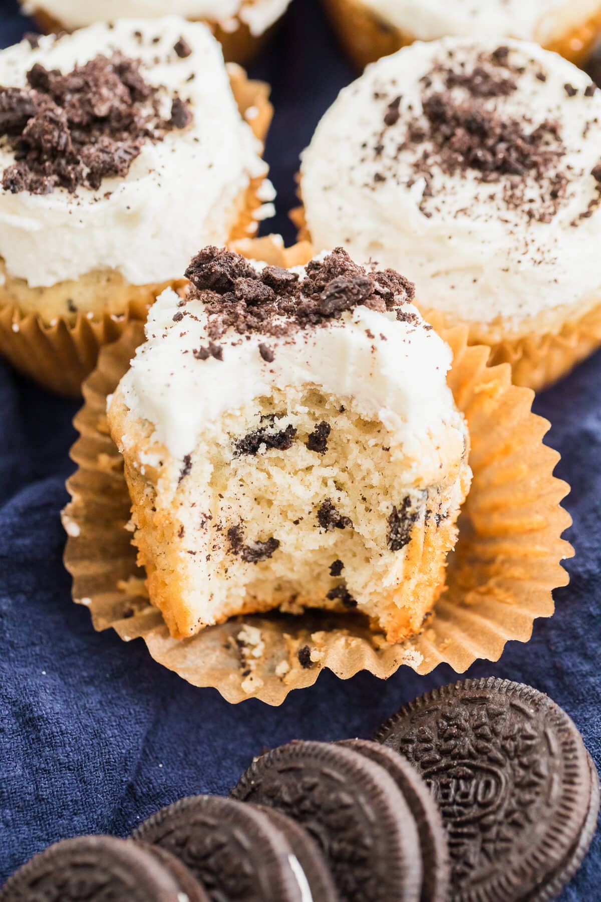 oreo cupcakes with vanilla buttercream and crushed oreos with bite taken out of the front one.