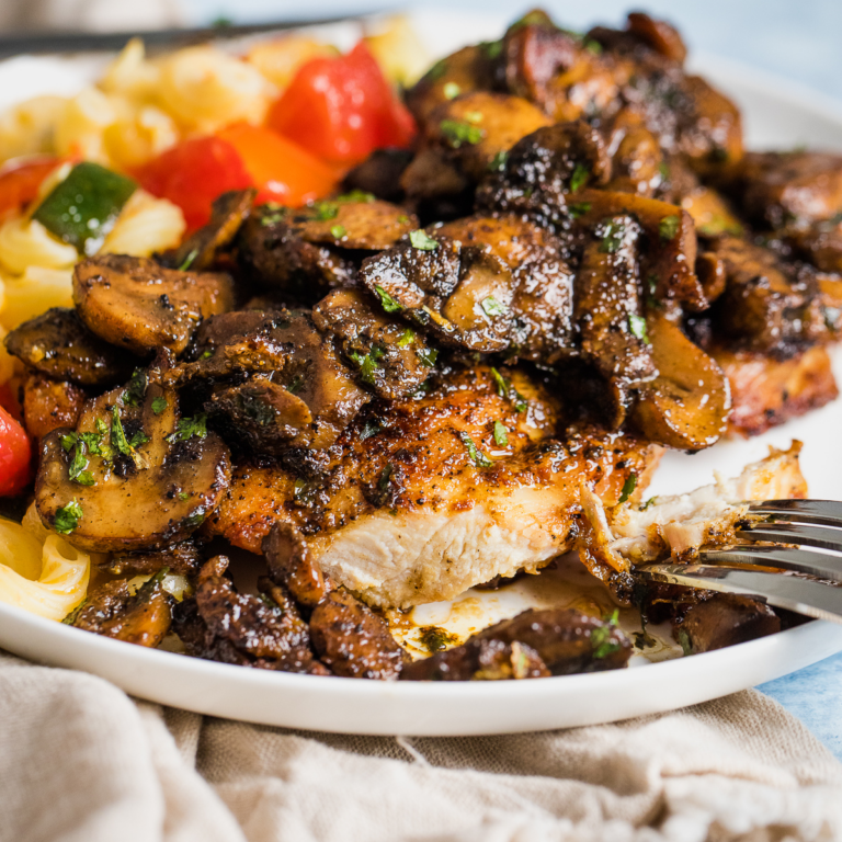 chicken and mushrooms on a plate with a side of vegetarian pasta salad.