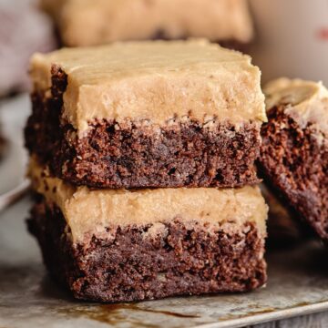 2 pieces of frosted coffee brownies stacked on a sheet pan.