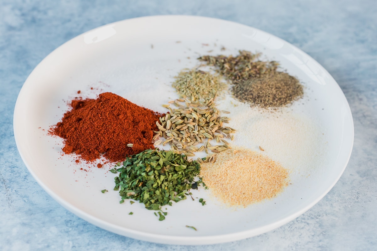 seasonings for sausage seasoning mix on a plate before being mixed.