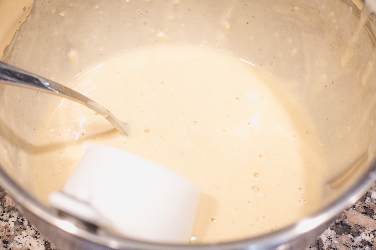 pancake batter with a measuring cup and spoon in a stainless steel bowl.