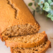 honey cake loaf with two slices on a cutting board with greenery to the right for Rosh Hashanah.
