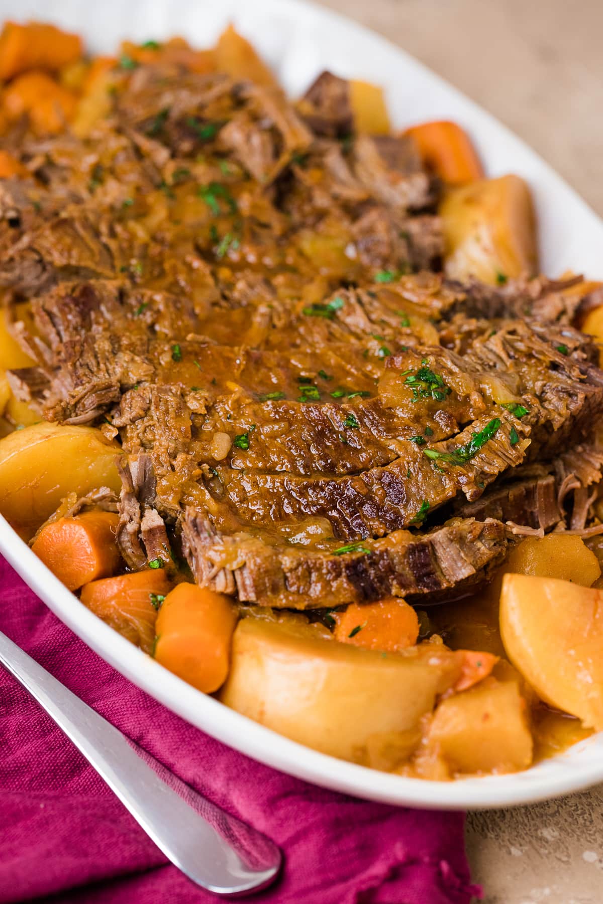 close up of Jewish brisket sliced on a platter with potatoes and carrots.