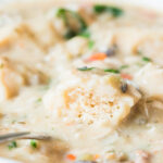 instant pot chicken and dumplings with a cut open dumpling in a white bowl.