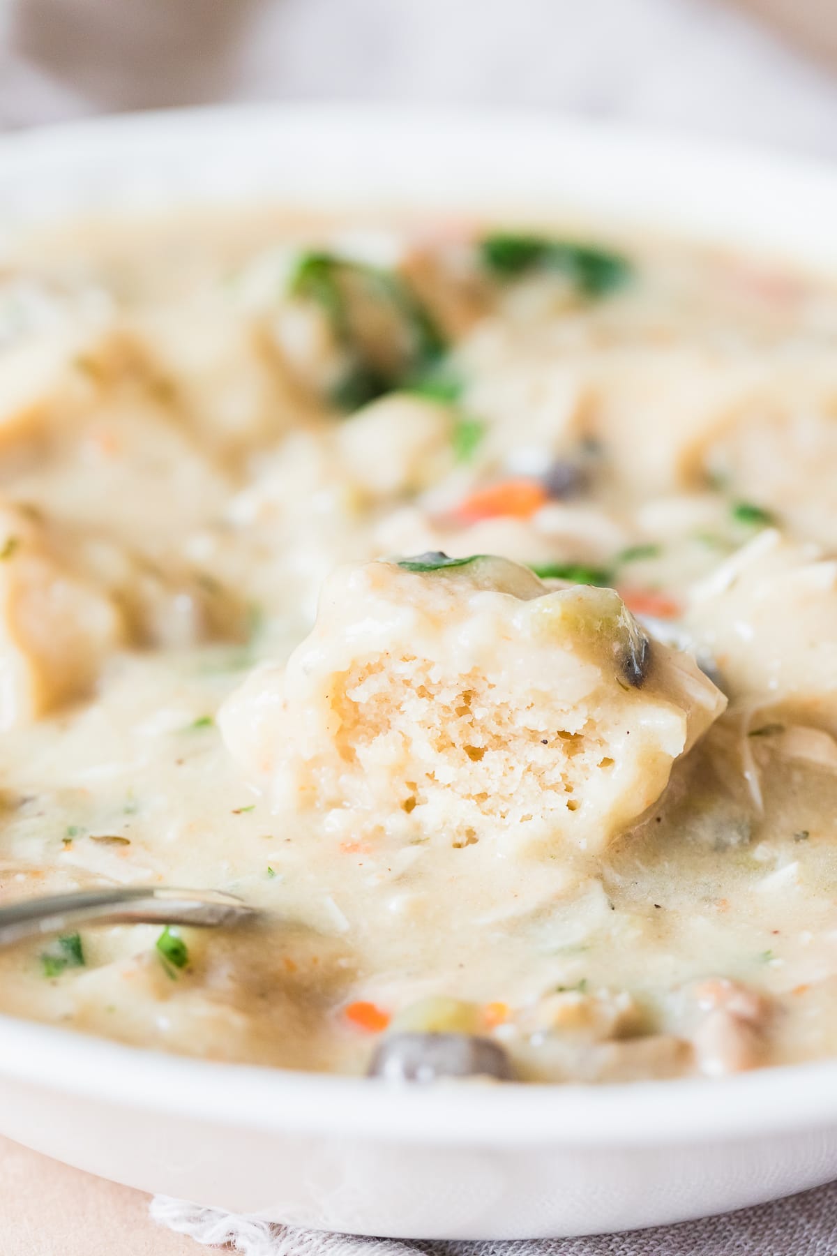 instant pot chicken and dumplings with a cut open dumpling in a white bowl.