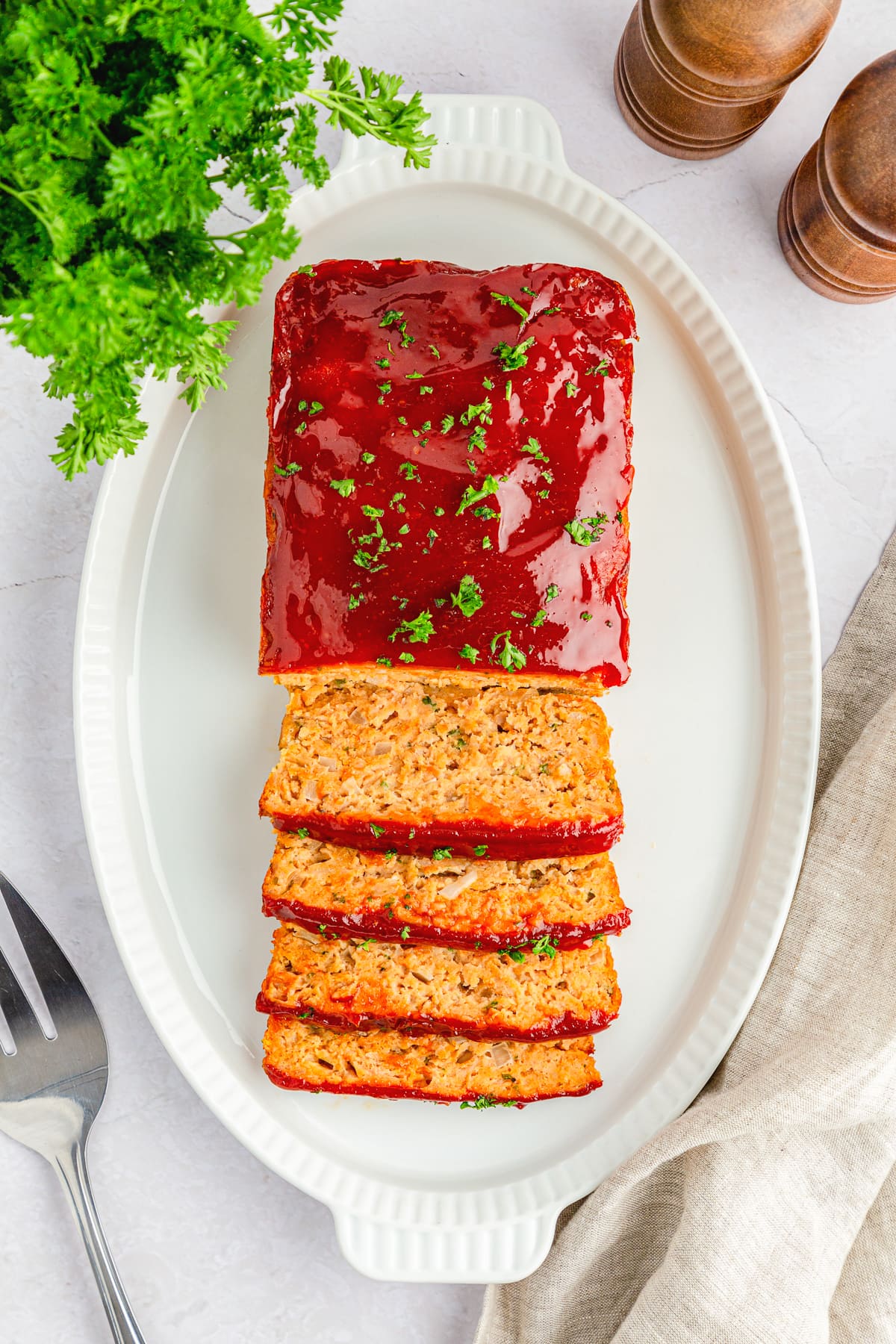 chicken meat loaf half sliced on a white platter.