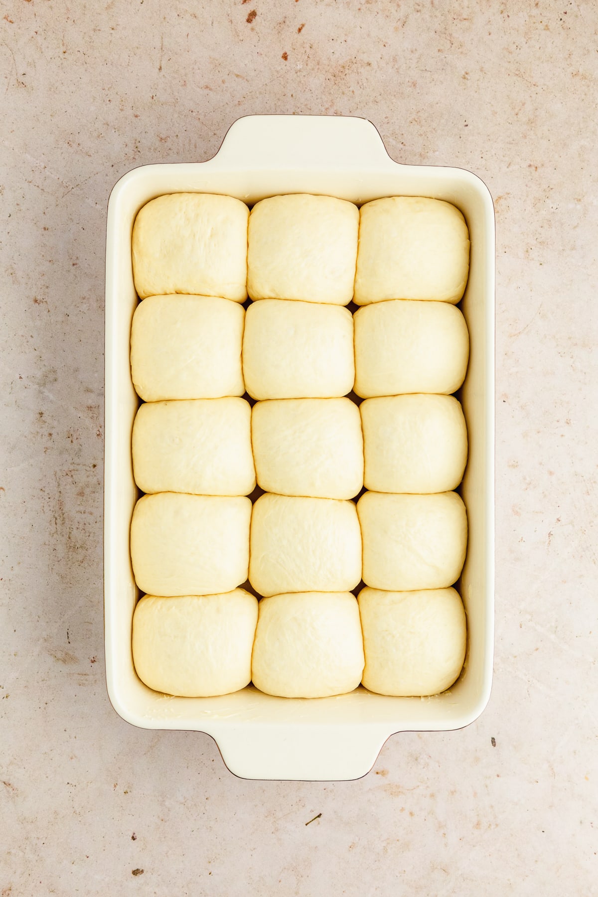 dinner rolls risen in a ceramic baking dish.