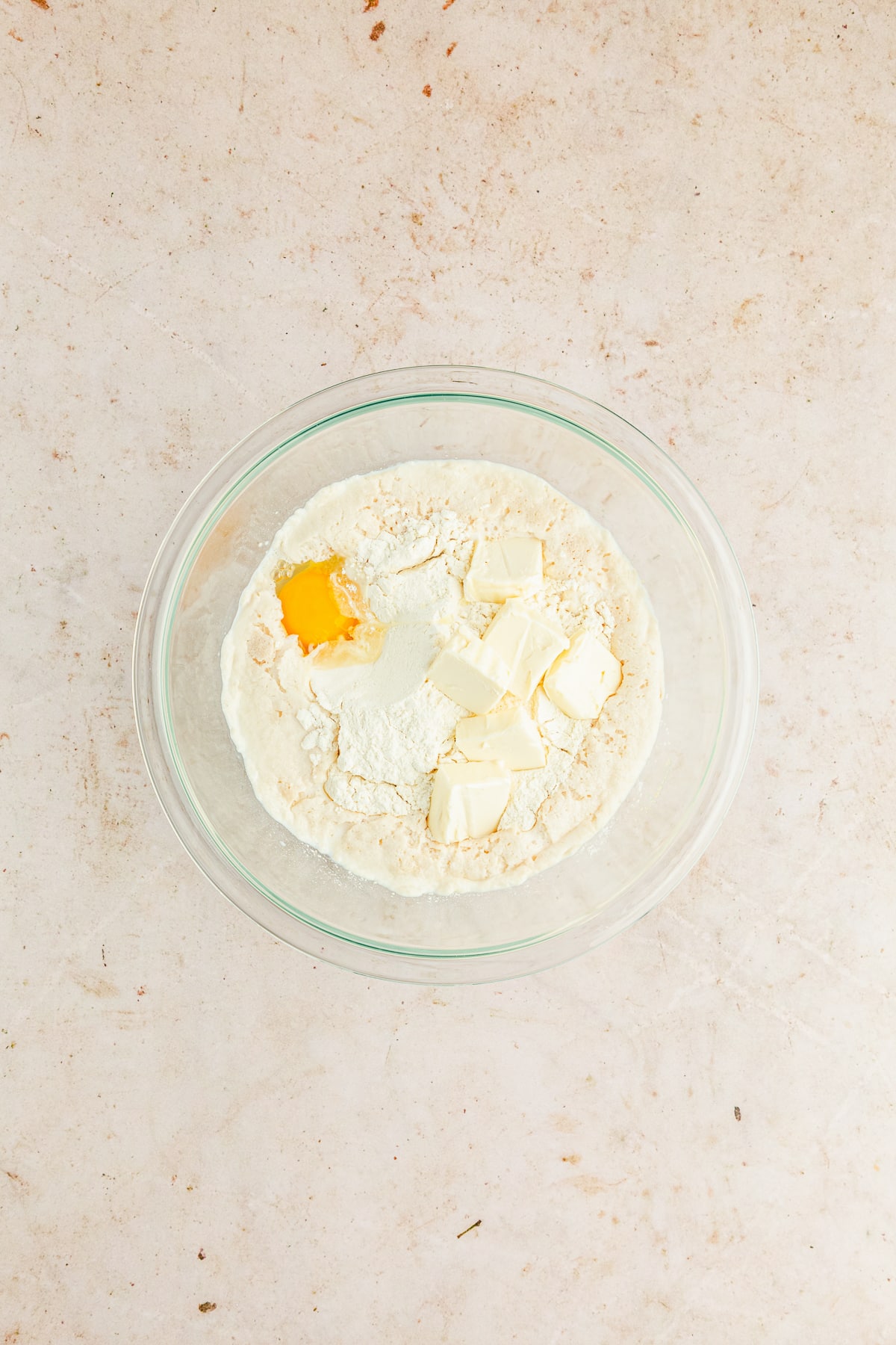 dough mixture with egg and butter for dinner rolls in a glass bowl.