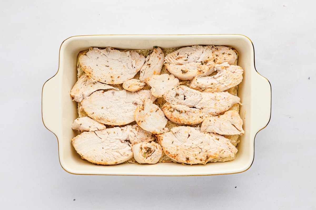 leftover roast turkey breast slices in a casserole dish over sliced Hawaiian rolls.