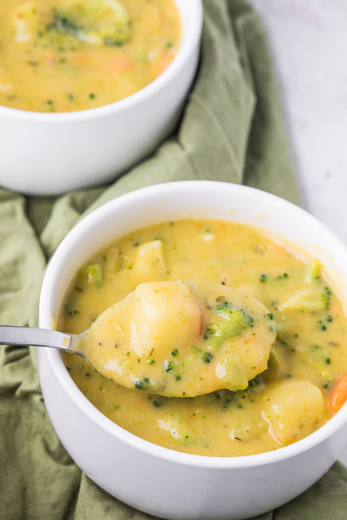 broccoli potato soup in a white bowl with a spoon.