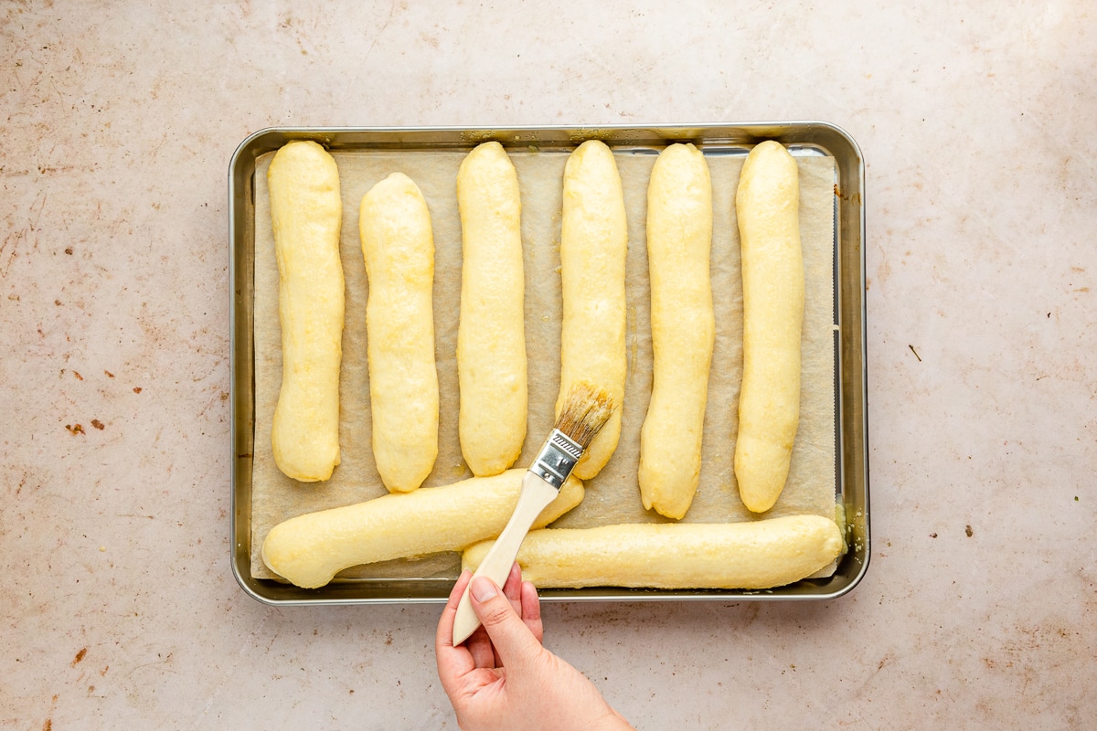 hand brushing butter onto breadsticks.