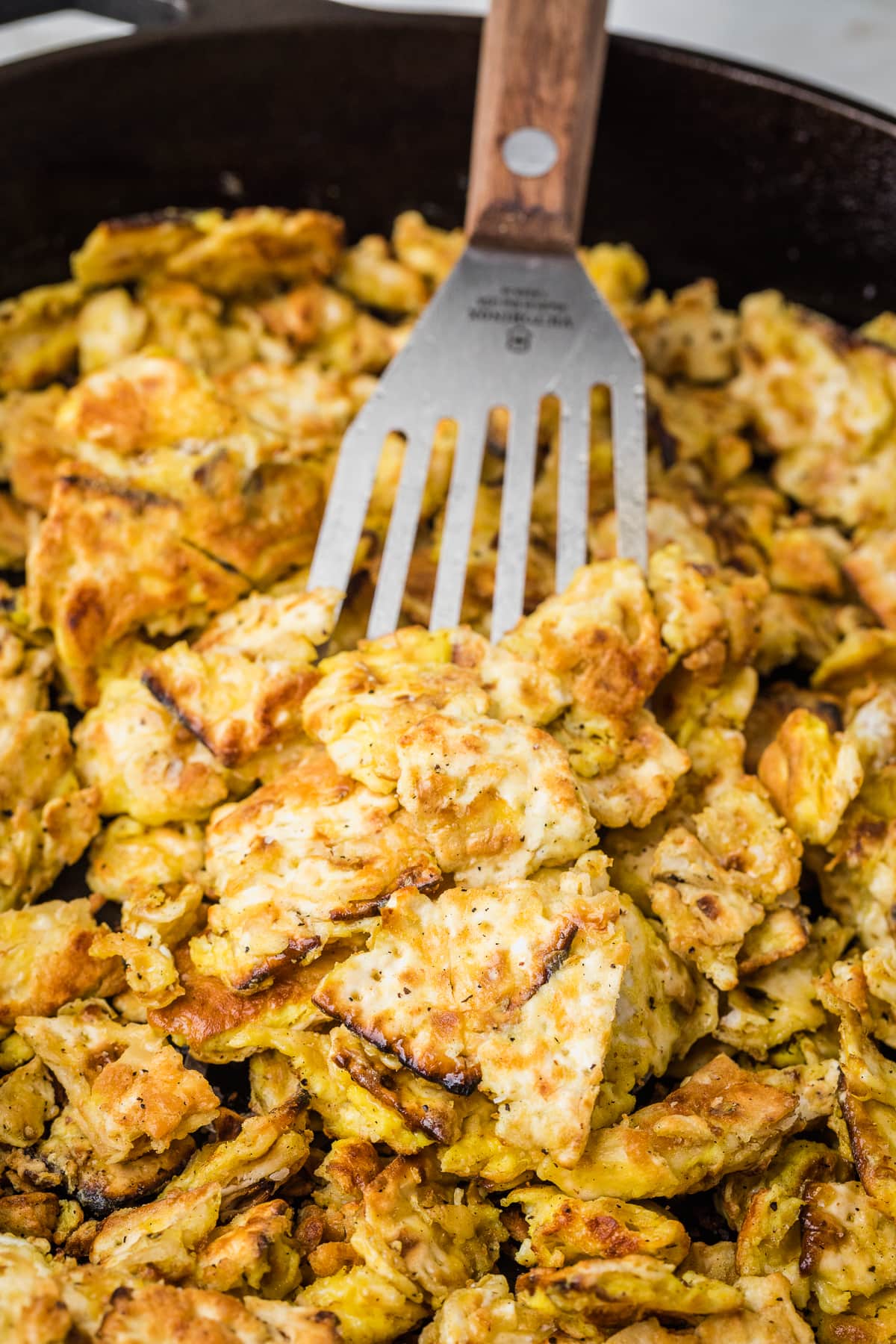 matzo brei in a cast iron skillet with a spatula.