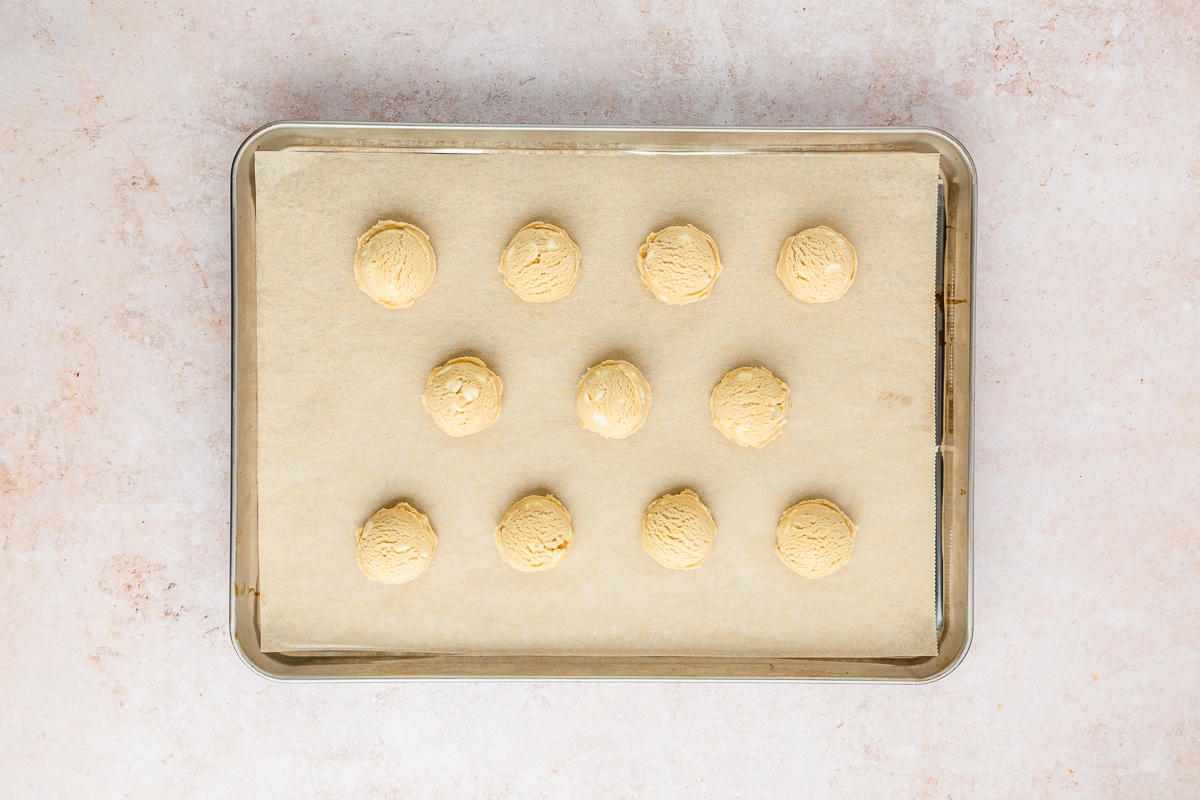 white chocolate chip cookie dough on a parchment lined baking sheet.