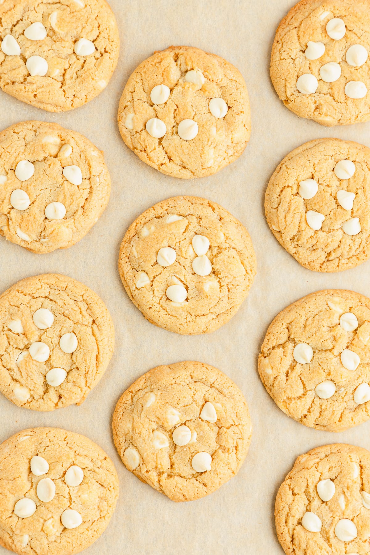 baked white chocolate chip cookies on a parchment lined baking sheet.