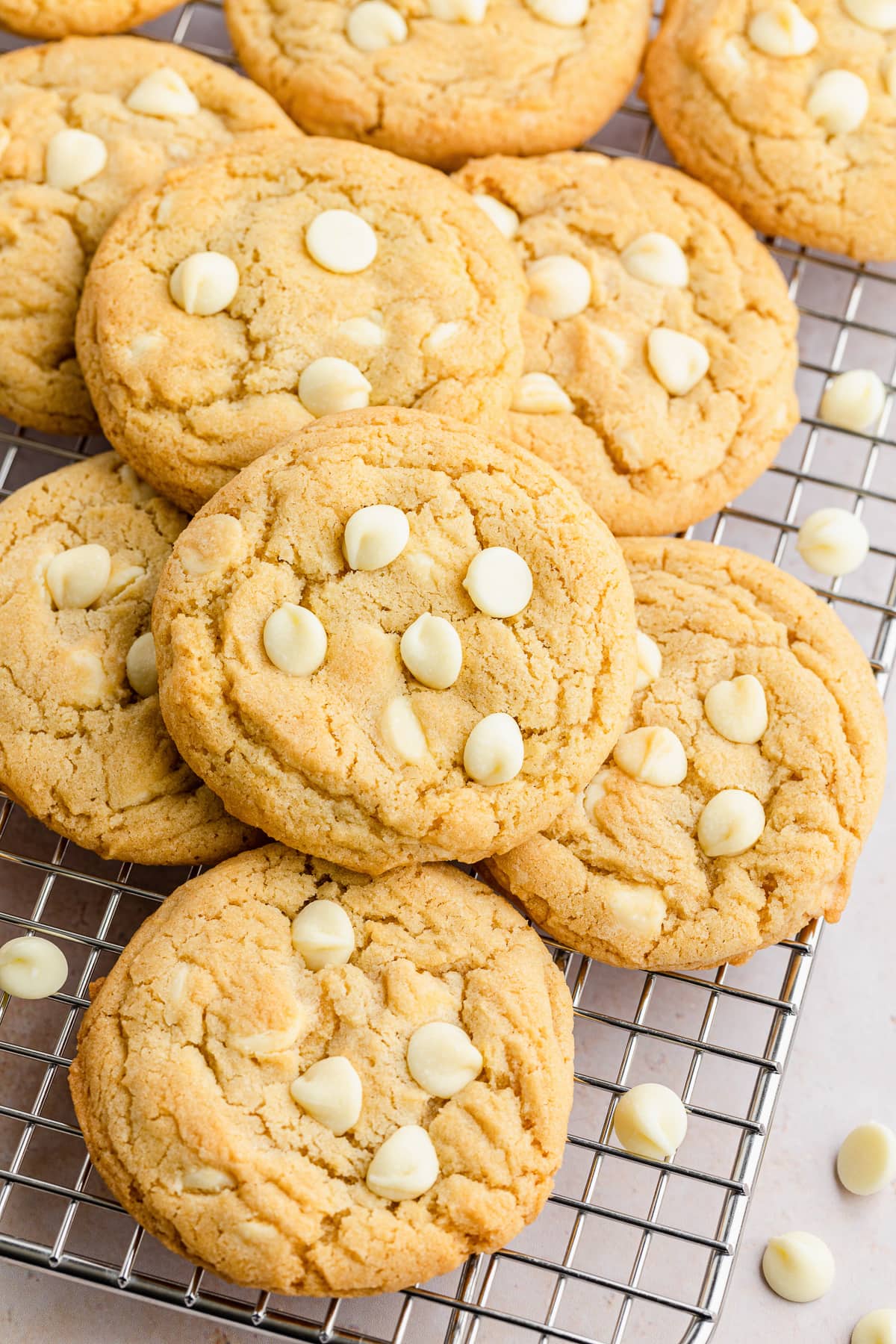 white chocolate chip cookies on a cooling rack on top of each other.
