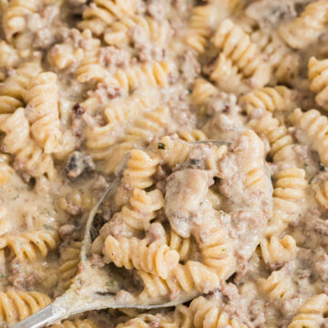 beef stroganoff in a skillet with a spoon scooping some.