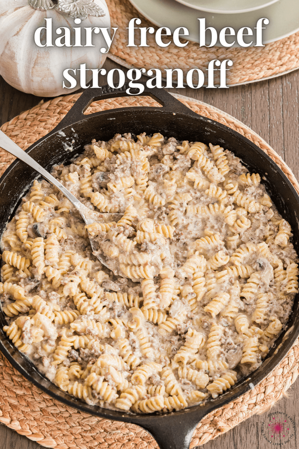 beef stroganoff in a cast iron skillet with serving spoon and text on image saying dairy free beef stroganoff.