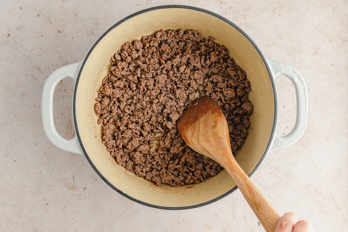 ground beef with a brown spoon in dutch oven.