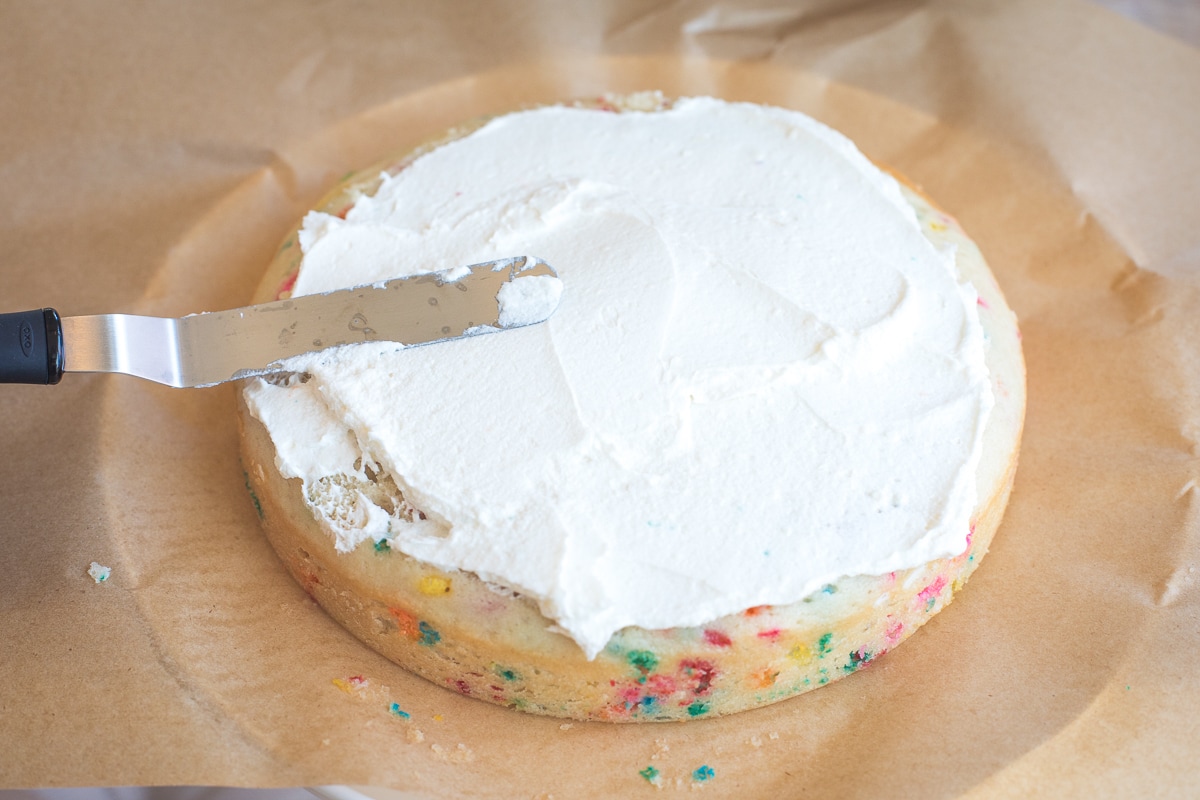 spatula spreading buttercream onto a cake.