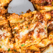 dairy free lasagna in a casserole dish with a metal spatula holding a slice.