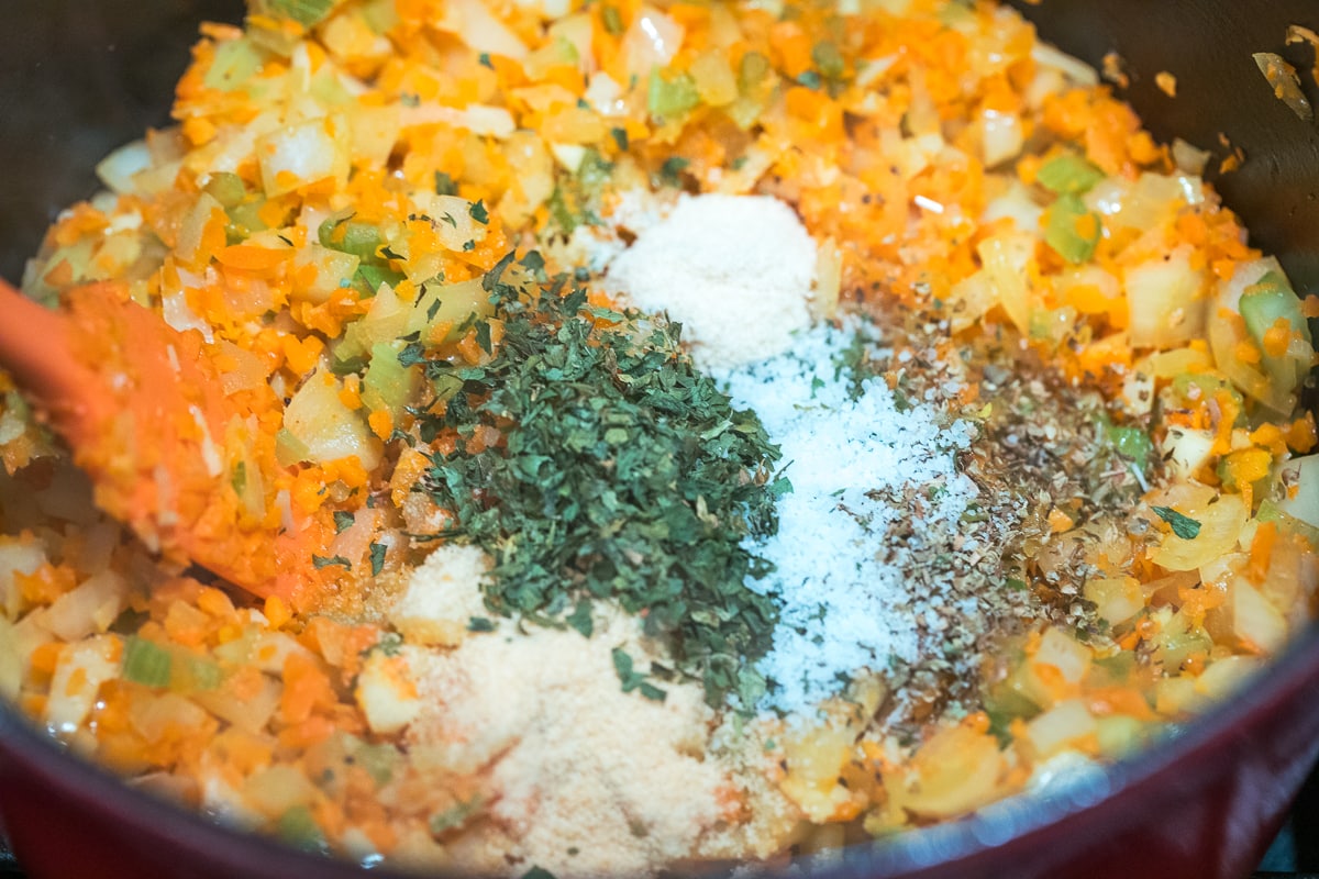 cooked mirepoix in a dutch oven with seasonings on top.