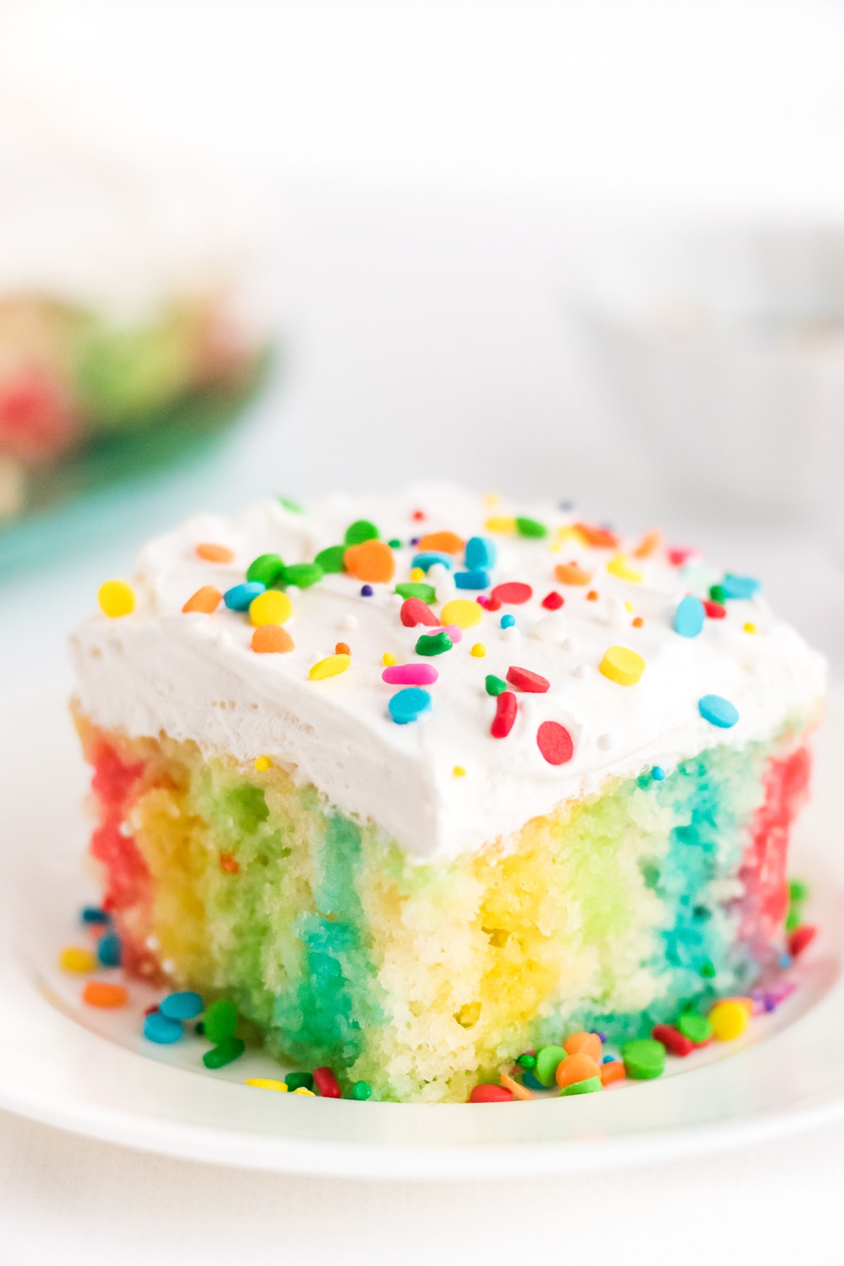 a piece of jello poke cake, rainbow colors on a plate.