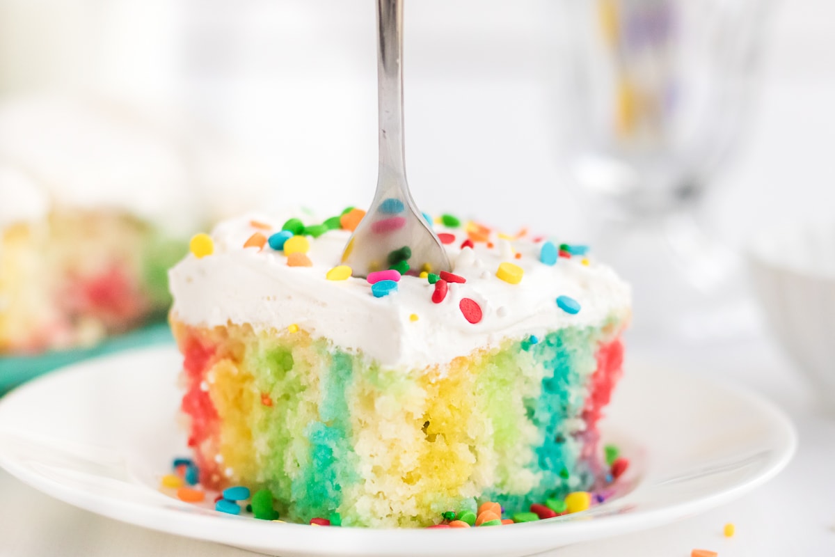 jello poke cake on a white plate with a fork sticking in it.