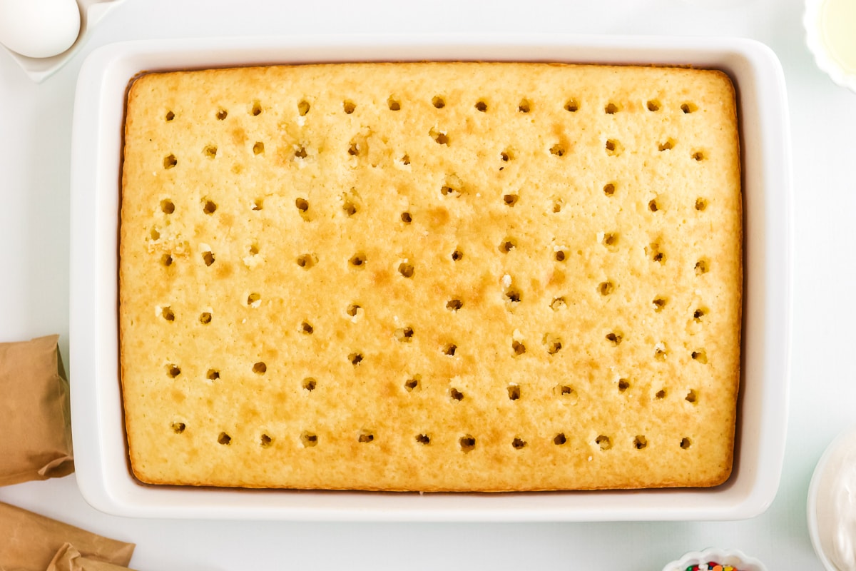 a prepped cake for poke cake with holes in it.