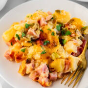 ham and cheese casserole on a white plate with a gold fork.
